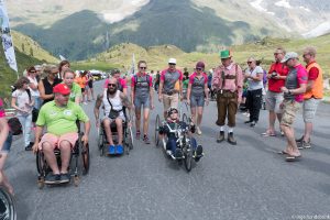 afbeelding mensen die in een rolstoel handbike of lopend een berg beklimmen