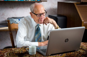 afbeelding oudere heer achter computer