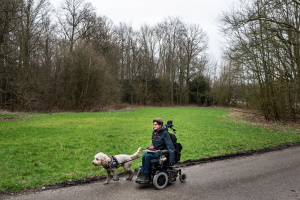 afbeelding vrouw in electrische rolstoel met hond in de natuur