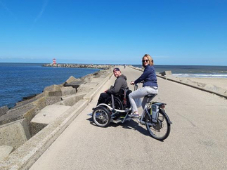 Afbeelding 2 personen met rolstoelfiets op havenhoofd Scheveningen