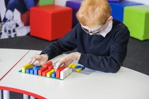 afbeelding blinde jongen met lego braille blokjes